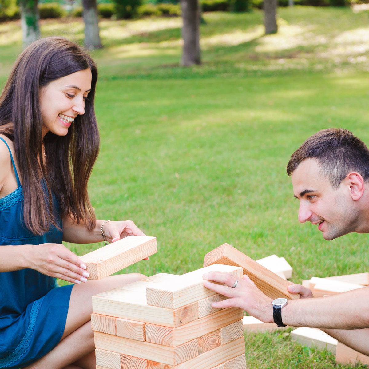 Mann und Frau spielen Jenga in einem grünen Park