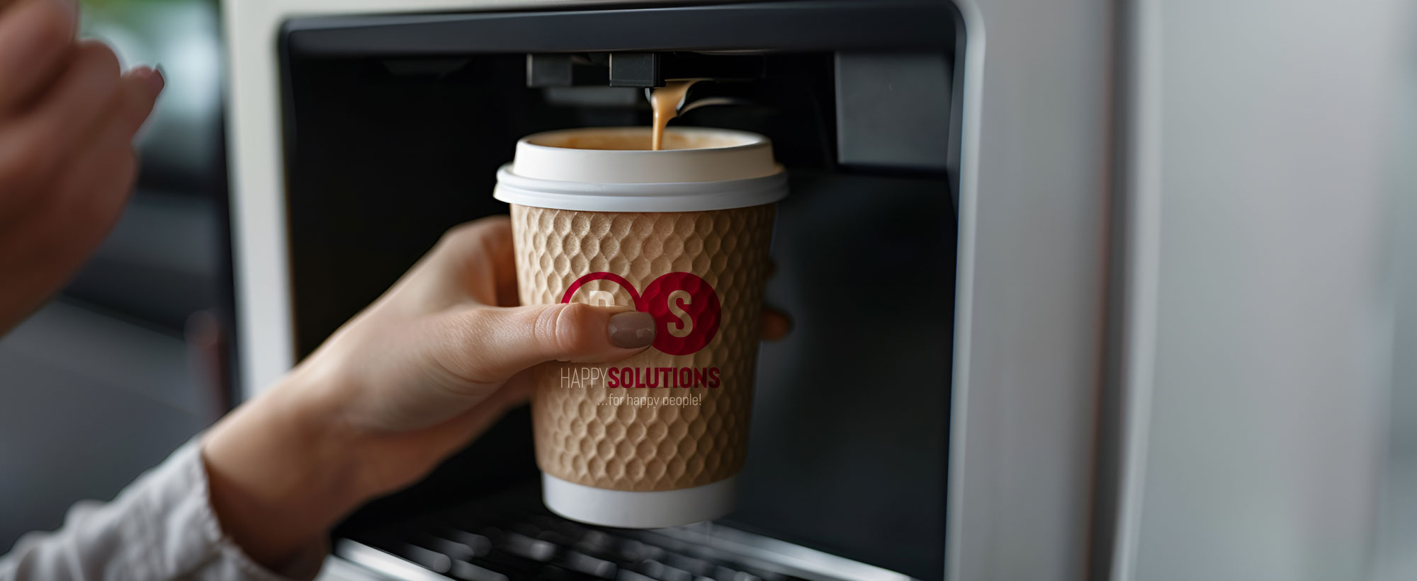 Frauenhand hält Kaffeebecher unter einen Kaffeeautomat