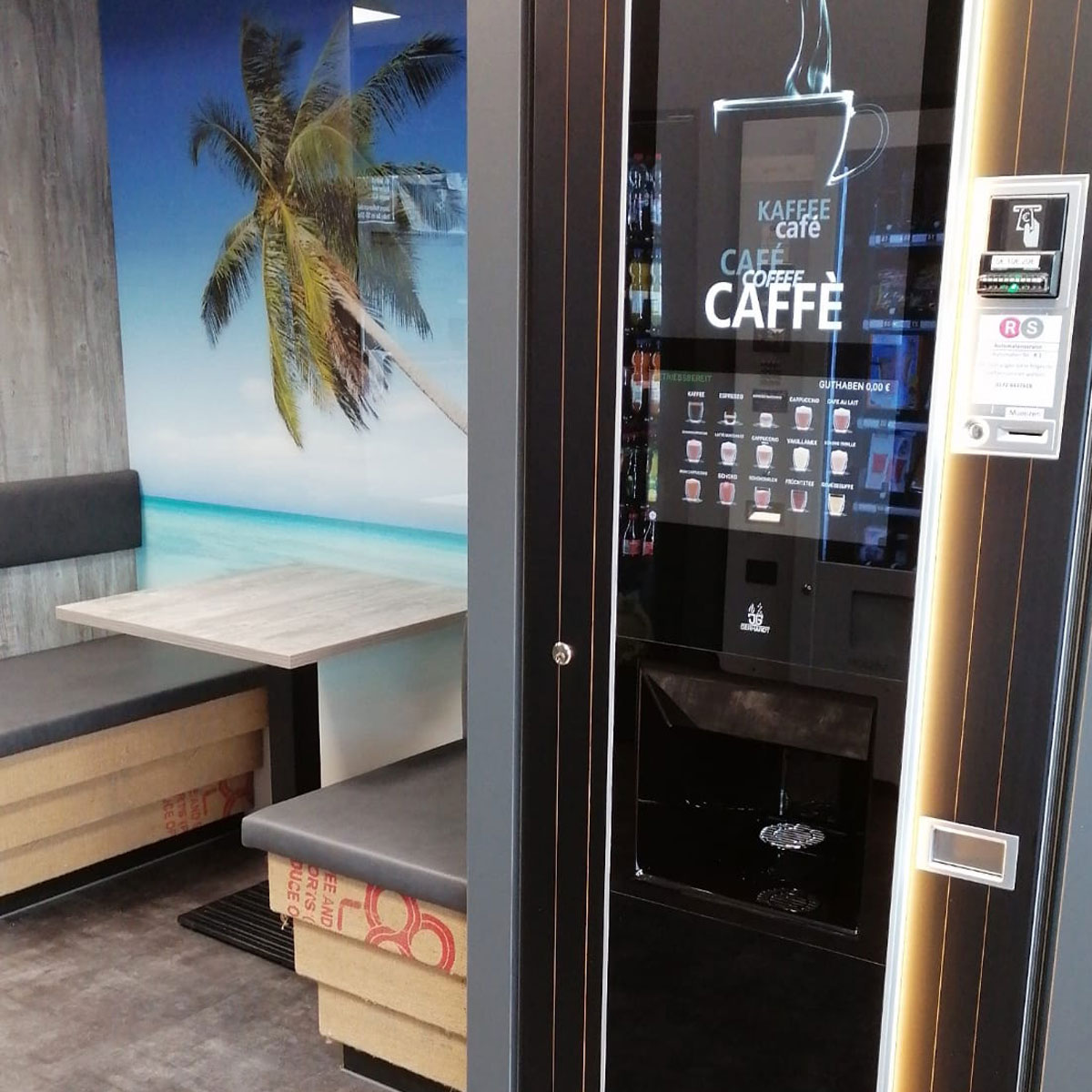 Großer Kaffeeautomat mit Sitzplätzen nebendran