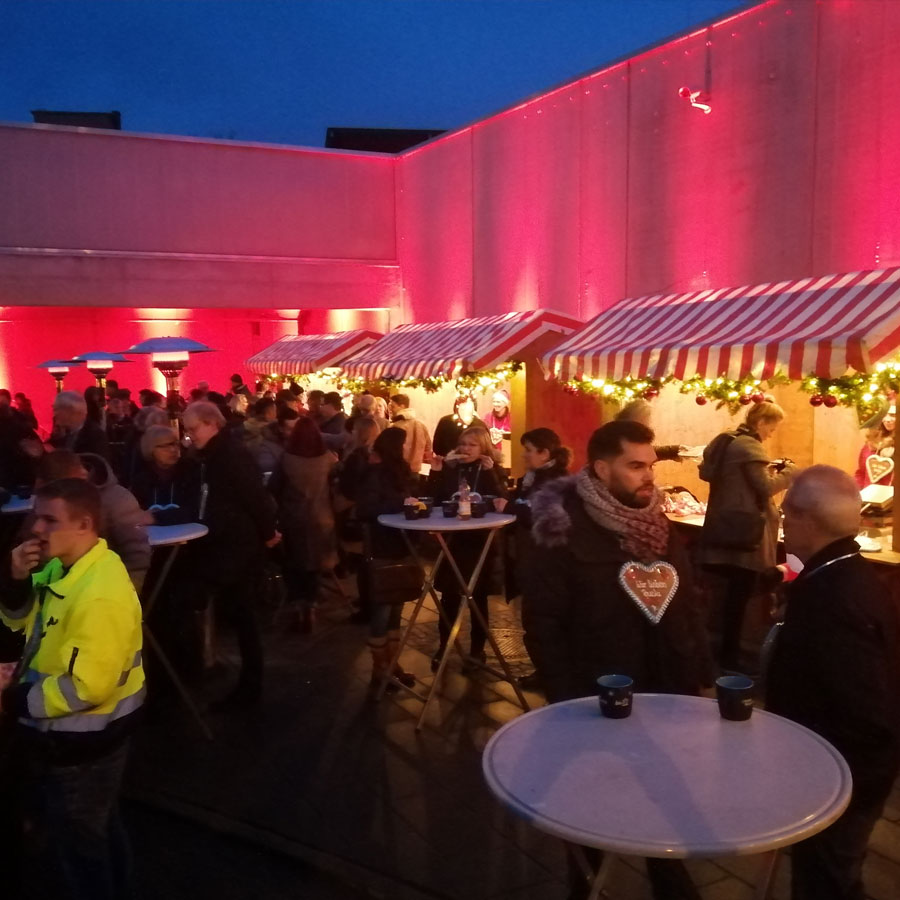 Personen stehen am Weihnachtsmarkt am Stehtisch
